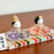 Porcelain and glass Hina dolls for Japan’s Girl’s Festival, with the Emperor in purple and the Empress in red, each decorated with delicate floral designs on a wooden platform.. Buy it in Malta at j-okini.com