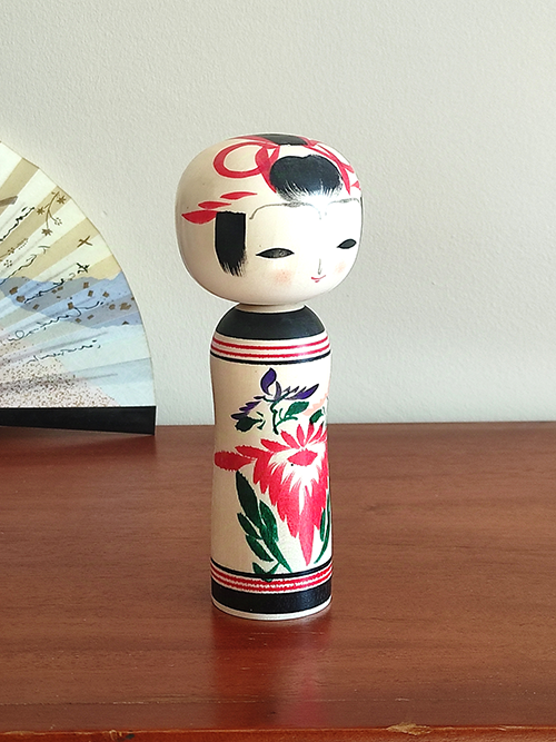 Cylindrical Creative Kokeshi doll by Miho Sasaki, featuring hand-painted chrysanthemums in red, green, and purple, with a rounded top and artist’s signature on the base. Buy online at j-okini.com in Malta