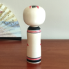 Cylindrical Creative Kokeshi doll by Miho Sasaki, featuring hand-painted chrysanthemums in red, green, and purple, with a rounded top and artist’s signature on the base. Buy online at j-okini.com in Malta