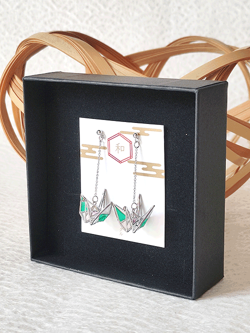 Origami crane earrings with a silver base and green and purple wings, handmade in Japan, packaged in a black gift box with a j-okini ribbon.