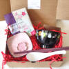 A beautifully packaged Totoro & Sakura gift box featuring a Totoro miso soup bowl, soup spoon, hexagonal chopsticks, sakura plate with matching chopstick rest, and a sakura-patterned double-sided gauze handkerchief.