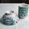 Banko-yaki Yunomi tea cup and rice bowl set featuring bold peony flowers with a vivid green background framed by traditional details, crafted by the Aigama kiln in Yokkaichi, Japan. Available at j-okini.com in Malta.