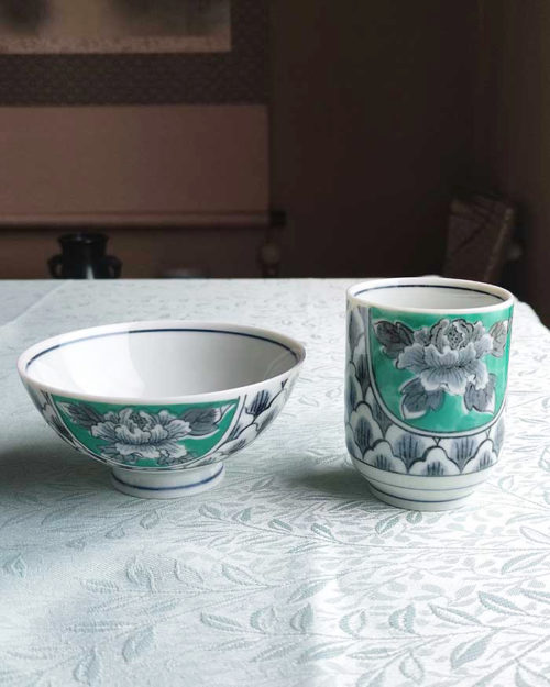 Banko-yaki Yunomi tea cup and rice bowl set featuring bold peony flowers with a vivid green background framed by traditional details, crafted by the Aigama kiln in Yokkaichi, Japan. Available at j-okini.com in Malta.