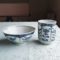 Banko-yaki Yunomi tea cup and rice bowl set featuring alternating floral motifs framed in rectangular panels, with delicate blue indigo hues, crafted by the Aigama kiln in Yokkaichi, Japan. Available at j-okini.com in Malta.