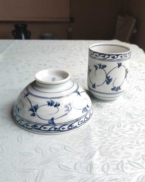 Banko-yaki Yunomi tea cup and rice bowl set in white Showcases elegant trailing vines with leaves in soft blue, encircling the cup and bowl in a flowing pattern. crafted by the Aigama kiln in Yokkaichi, Japan. Available at j-okini.com in Malta