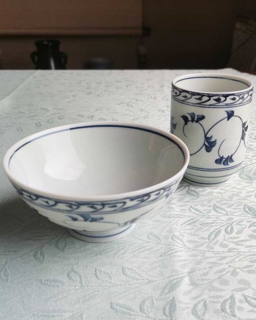 Banko-yaki Yunomi tea cup and rice bowl set in white Showcases elegant trailing vines with leaves in soft blue, encircling the cup and bowl in a flowing pattern. crafted by the Aigama kiln in Yokkaichi, Japan. Available at j-okini.com in Malta