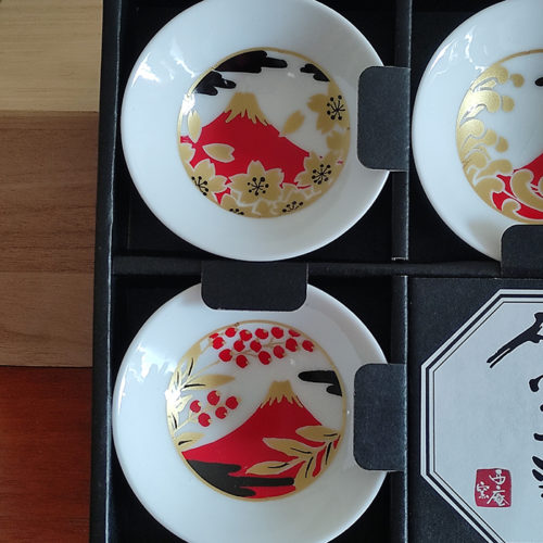 A 5-piece Sakazuki sake cup set featuring Red Fuji with intricate designs of cherry blossoms, waves, and autumn leaves, accented in gold and red for an elegant, celebratory touch. Available at j-okini.com in Malta