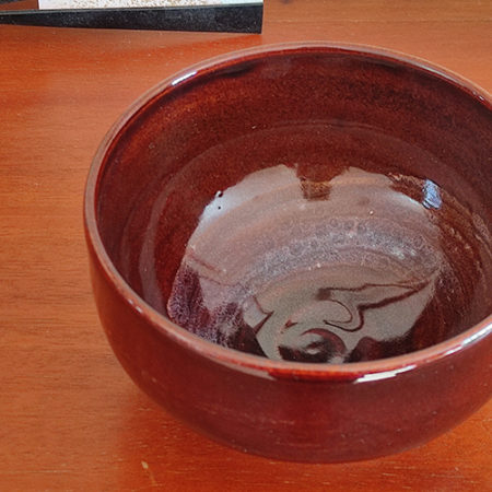 A handmade Kiyomizu-ware Matcha bowl by Okayama Kousha, featuring a deep amber glaze with vibrant blue accents, a low tube shape, and a wide opening for easy use. available at j-okini.com in malta