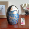 A handcrafted Japanese Kokeshi doll named 'Banshu' by Sekiguchi Toua, standing 16.5 cm tall, featuring a deep blue kimono with gold-painted pampas grass, a moon, and subtle glitters for a shimmering effect, symbolizing late autumn. Available at j-okini.com in Malta