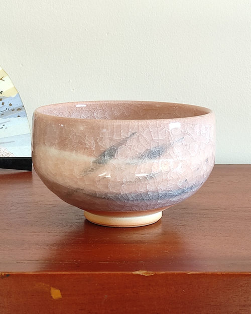 Kiyomizu-ware handmade Matcha bowl by Okayama Kousha, featuring a warm light coral and skin-tone hue with a delicate cracked-glass pattern. Tube-shaped for excellent heat retention, with unique random grey accents on the front. Stamped at the bottom. Made in Japan. Available at j-okini.com in Malta