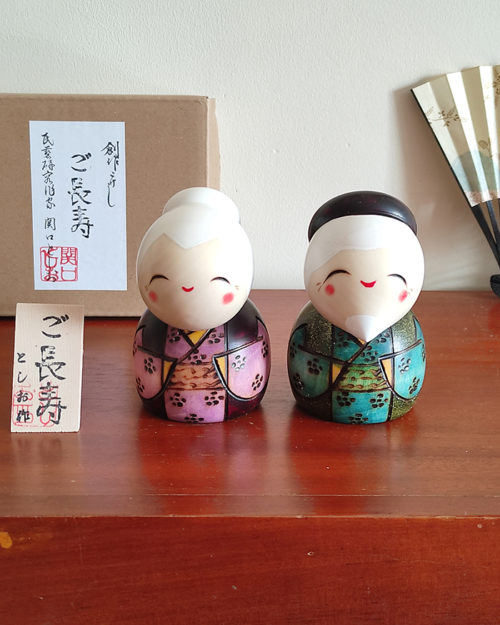 A modern Creative Kokeshi doll set named 'Gochouju' by award-winning artist Sekiguchi Toshio. The dolls depict an elderly couple with kind smiles, dressed in elegant kimono, celebrating longevity and happiness. Handcrafted in Japan. Available at j-okini.com in Malta