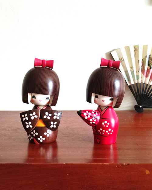 Handcrafted Japanese Kokeshi doll 'Kosode' by artist Kojo, wearing a chic brown kimono with a soft pink collar and a vibrant yellow obi. Available at j-okini.com in Malta