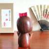 Handcrafted Japanese Kokeshi doll 'Kosode' by artist Kojo, wearing a chic brown kimono with a soft pink collar and a vibrant yellow obi. Available at j-okini.com in Malta