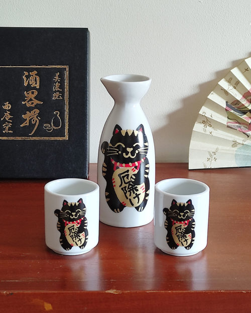 Mino ware porcelain sake set featuring a black Maneki Neko with a smiley face, symbolizing protection and good fortune. Available at j-okini.com in Malta