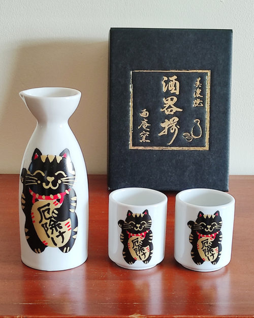 Mino ware porcelain sake set featuring a black Maneki Neko with a smiley face, symbolizing protection and good fortune. Available at j-okini.com in Malta