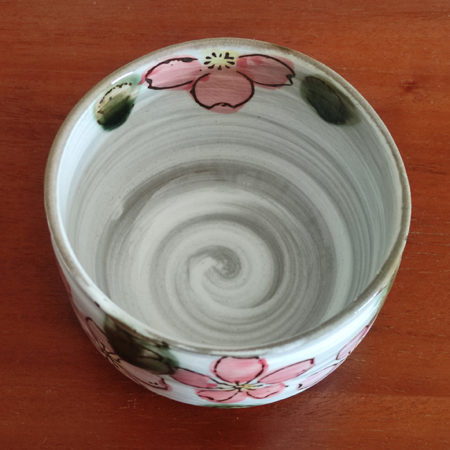 Mino ware Matcha bowl featuring a red Sakura blossom design with dark green leaves, a winding dark green-brown rim, and a swirl pattern inside. Made in Japan. Available at j-okini.com in Malta