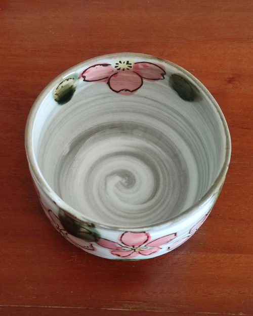 Mino ware Matcha bowl featuring a red Sakura blossom design with dark green leaves, a winding dark green-brown rim, and a swirl pattern inside. Made in Japan. Available at j-okini.com in Malta