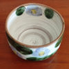 Mino ware Matcha bowl featuring a purple Camellia design with green leaves, a winding dark green-brown rim, and a swirl pattern inside. Made in Japan. Available at j-okini.com in Malta