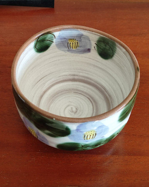 Mino ware Matcha bowl featuring a purple Camellia design with green leaves, a winding dark green-brown rim, and a swirl pattern inside. Made in Japan. Available at j-okini.com in Malta