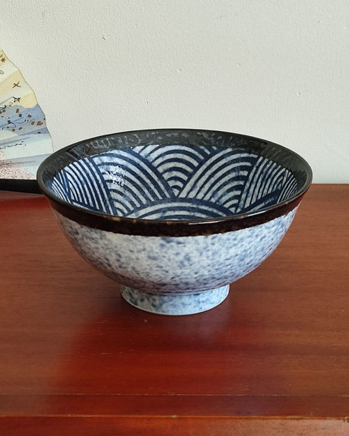 A traditional Japanese Mino ware donburi bowl featuring a deep blue Seigaiha wave pattern. With a 600ml capacity, 16cm diameter, and 8cm height, it's ideal for rice dishes, udon, or instant noodles. Beautifully crafted with a smooth glaze, showcasing the elegance of Japanese ceramics. Made in Japan. Available at j-okini.com in Malta