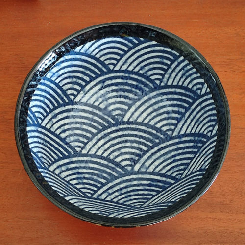 A traditional Japanese Mino ware donburi bowl featuring a deep blue Seigaiha wave pattern. With a 600ml capacity, 16cm diameter, and 8cm height, it's ideal for rice dishes, udon, or instant noodles. Beautifully crafted with a smooth glaze, showcasing the elegance of Japanese ceramics. Made in Japan. Available at j-okini.com in Malta