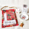 Lucky Cat Blessings Set featuring a red Japanese Goshuincho accordion notebook with a matching drawstring pouch, a white porcelain Maneki-neko small dish, a Banko Ware Feng Shui white Maneki-neko ceramic figurine, and a handmade Chirimen Cats’ Netsuke strap. A charming collection of Japanese lucky cat-themed items, perfect for gifts or personal good fortune. Made in Japan. Available at j-okini.com in Malta.