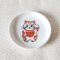 A charming Maneki-Neko small dish made from white porcelain, featuring a lucky cat with red and gold patches and the 福 (Fuku) character symbolizing happiness. Perfect for serving soy sauce or small appetizers, or as a decorative accent. Made in Japan, handcrafted Mino ware. Available at j-okini.com in Malta