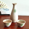 A glazed Kiseto Sake Set with a beige tokkuri bottle and matching sake cups, each featuring soft green accents and a smooth, speckled finish. Made in Japan. Available at j-okini.com in Malta