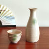 A glazed Kiseto Sake Set with a beige tokkuri bottle and matching sake cups, each featuring soft green accents and a smooth, speckled finish. Made in Japan. Available at j-okini.com in Malta