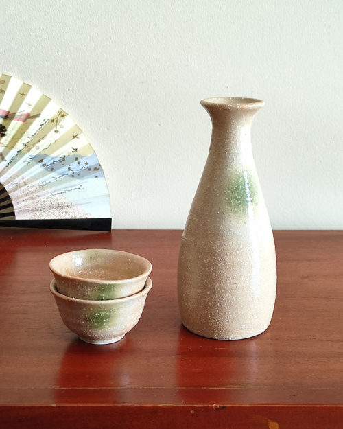 A glazed Kiseto Sake Set with a beige tokkuri bottle and matching sake cups, each featuring soft green accents and a smooth, speckled finish. Made in Japan. Available at j-okini.com in Malta